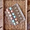 farm-fresh eggs, pastured eggs, colored eggs in carton sitting on woven tray.